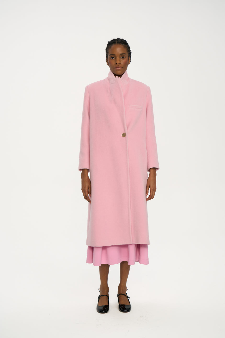 Powder pink single-breasted wool coat with high collar styled over matching pink dress, full length front view on model – Inner Tiger