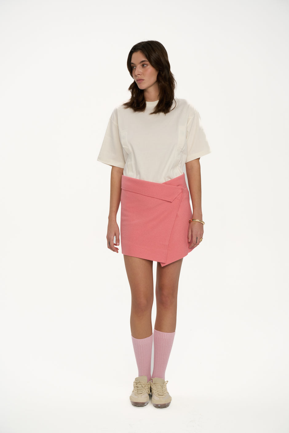 Powder pink wrap mini skirt styled with oversized cream T-shirt, pink socks and sneakers on model, full length front view – Inner Tiger