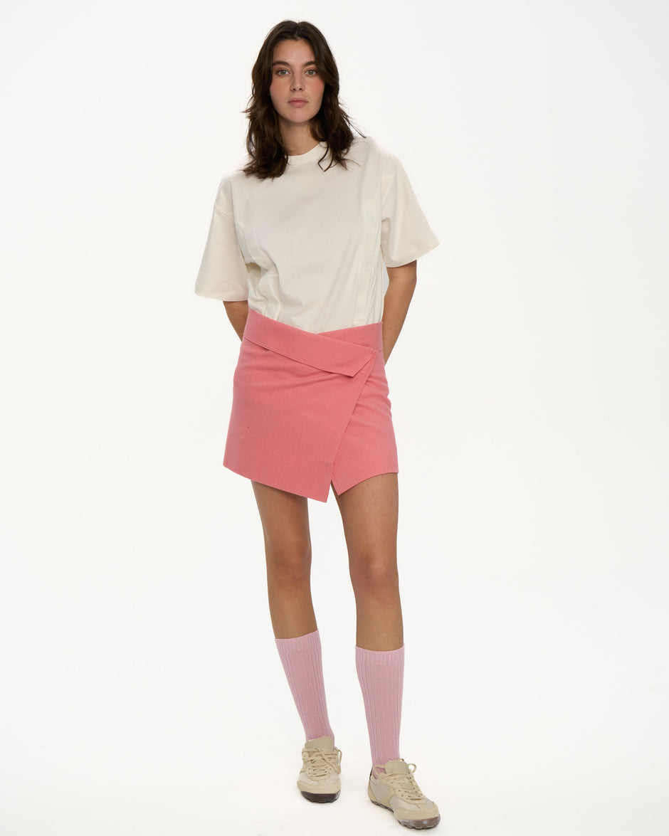 Powder pink wrap mini skirt styled with oversized cream T-shirt, pink socks and sneakers on model, full length front view – Inner Tiger