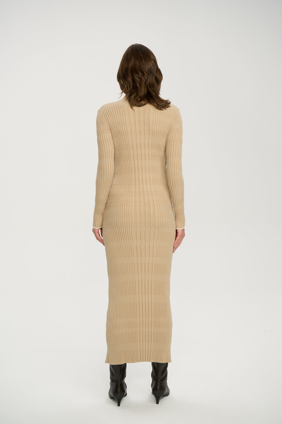 Woman wearing a beige ribbed dress on a white background