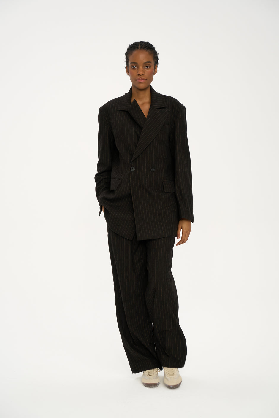 Front view of dark chocolate pinstripe tailored trousers with soft drape and full-length hem on model – Inner Tiger