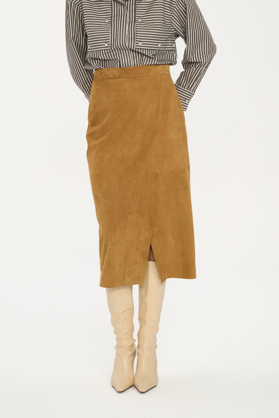 Brown suede skirt worn with a striped shirt and beige boots on a white background