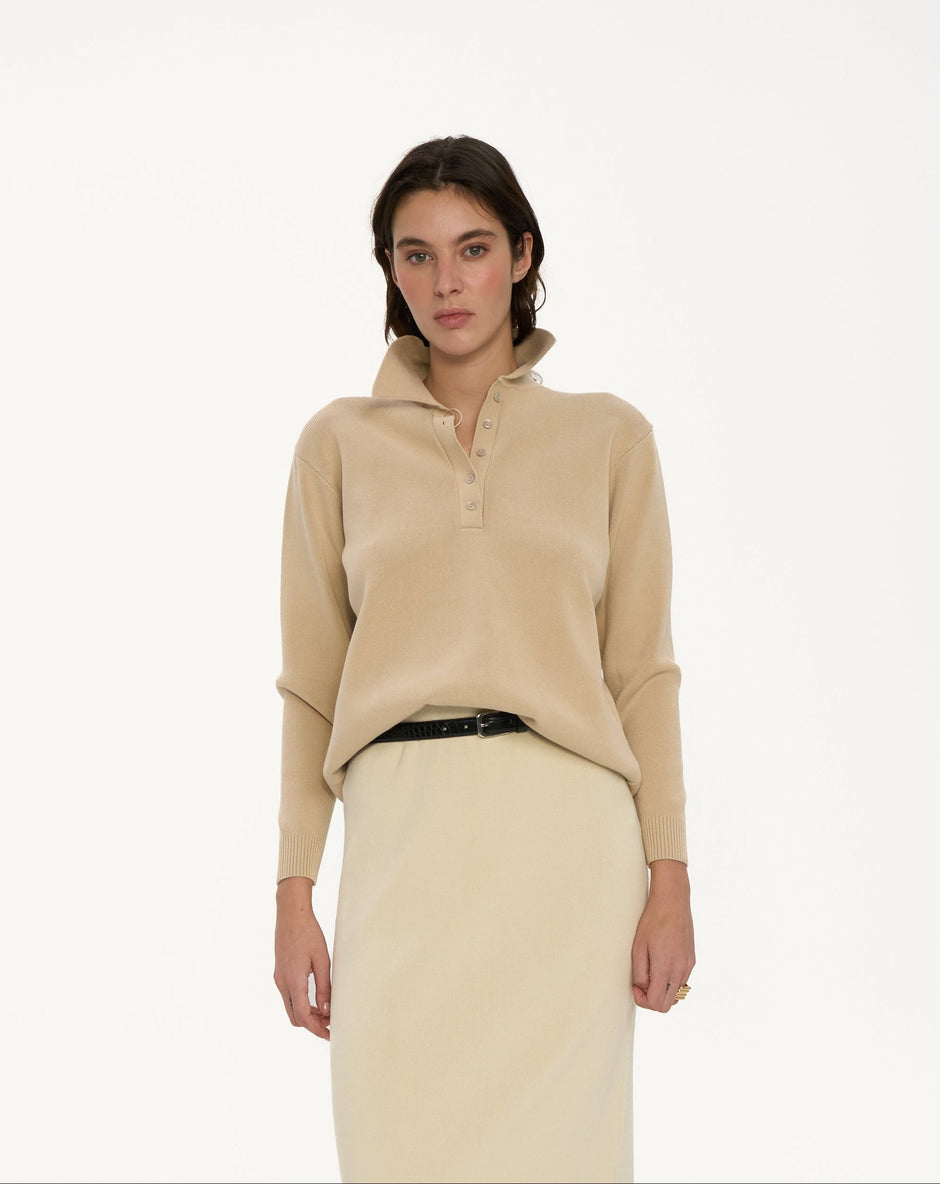 Woman wearing a beige sweater and skirt on a white background