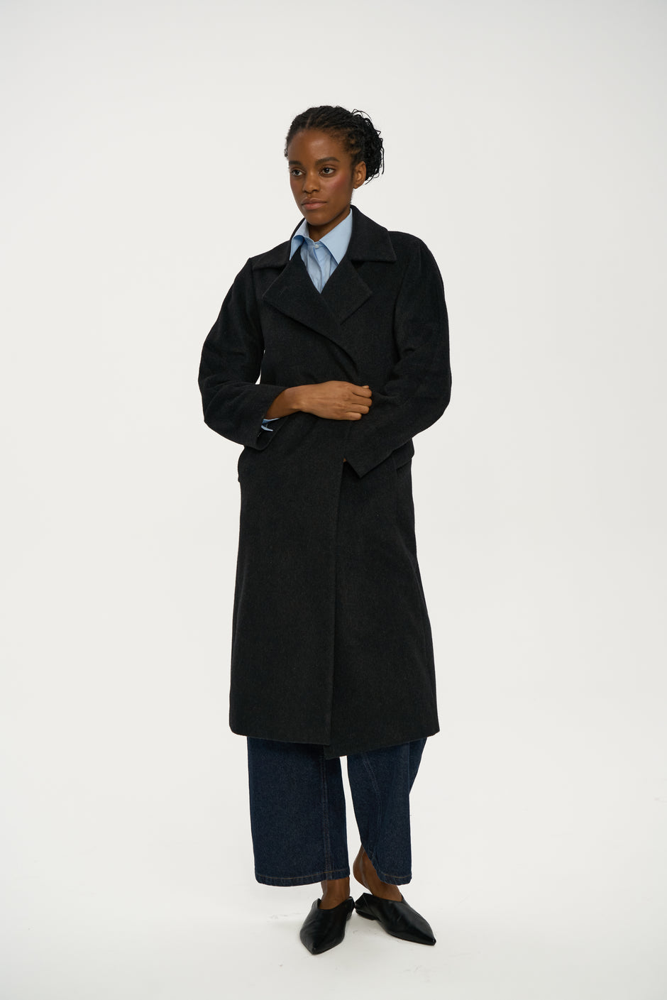 Model wearing a black coat on a white background