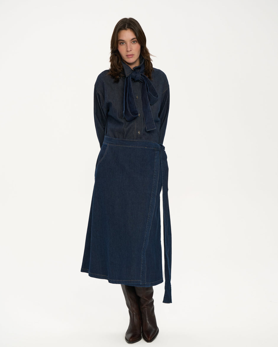 Person wearing a dark blue outfit with a skirt on a white background