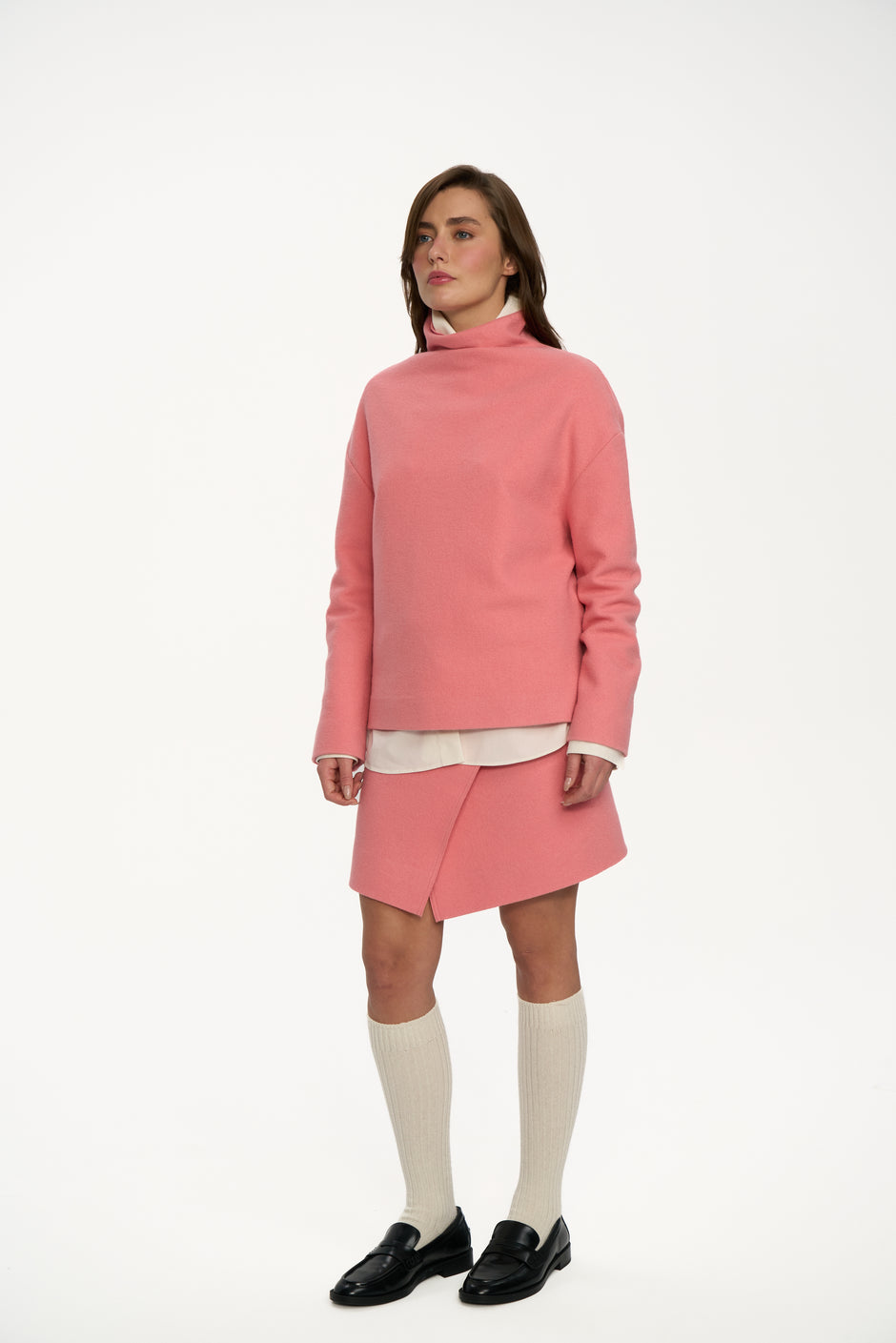Side view of powder pink wool sweater and asymmetric wrap mini skirt styled with cream knee-high socks and black loafers – Inner Tiger