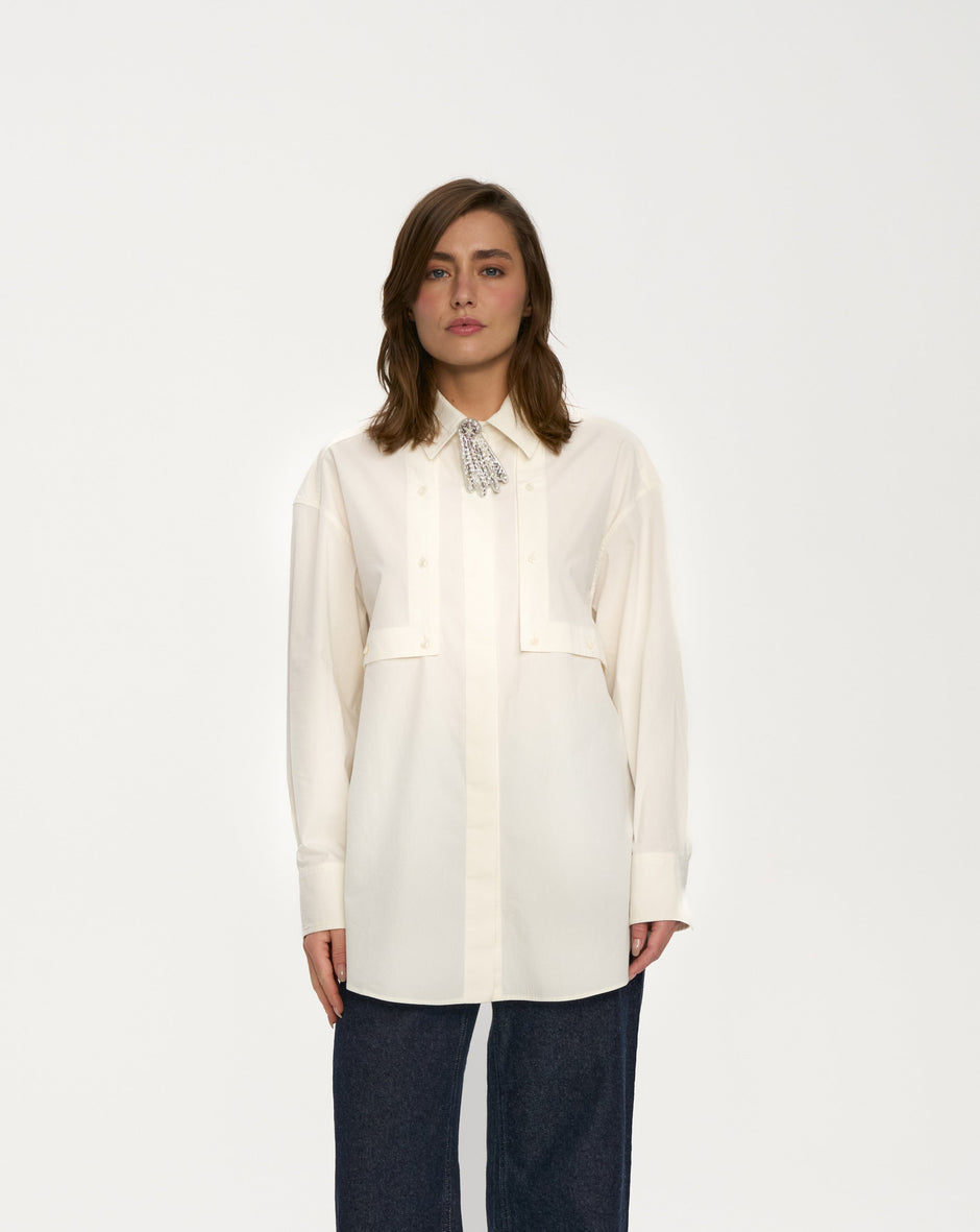 Person wearing a white blouse and dark pants on a white background