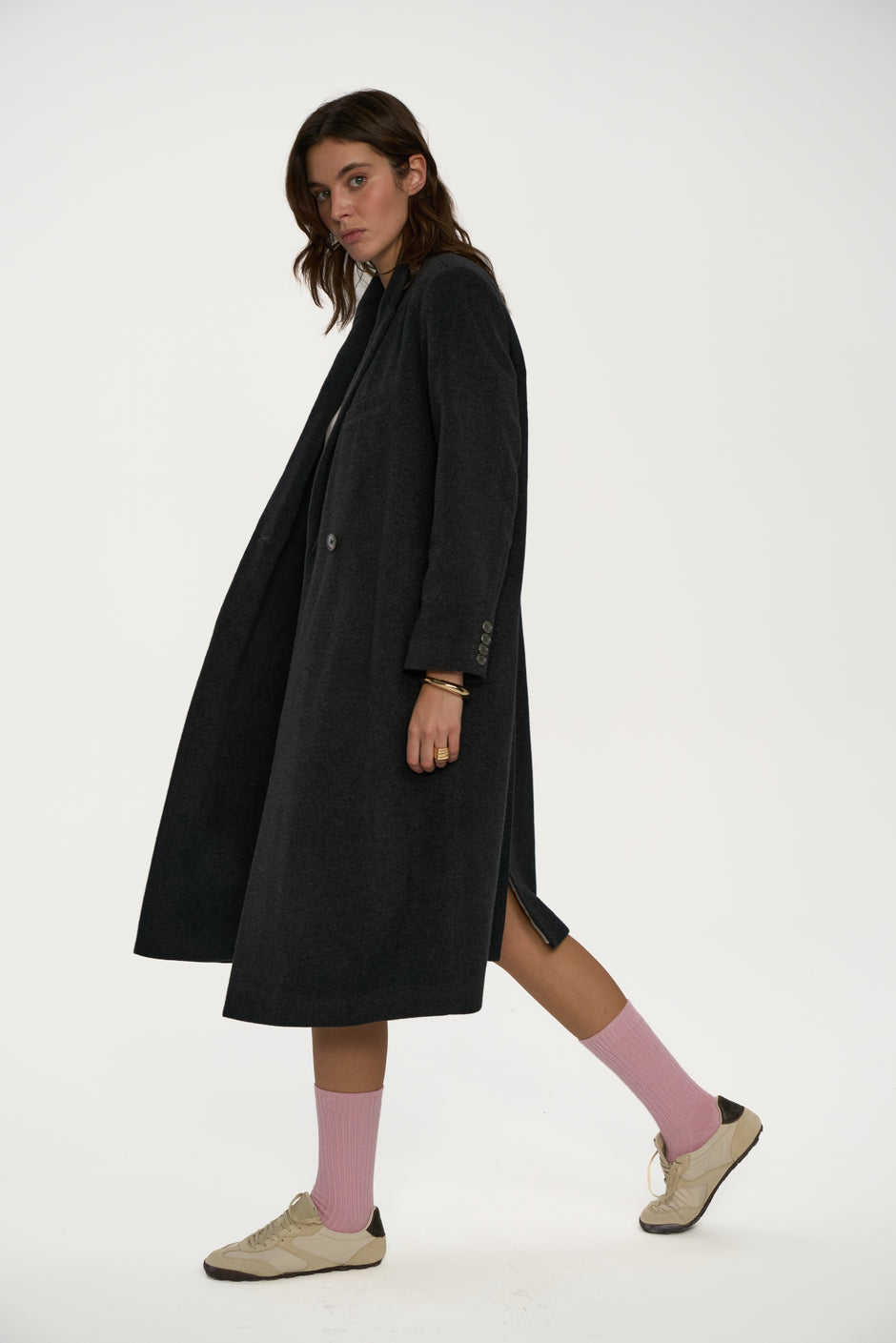 Woman wearing a long black coat and pink socks on a white background