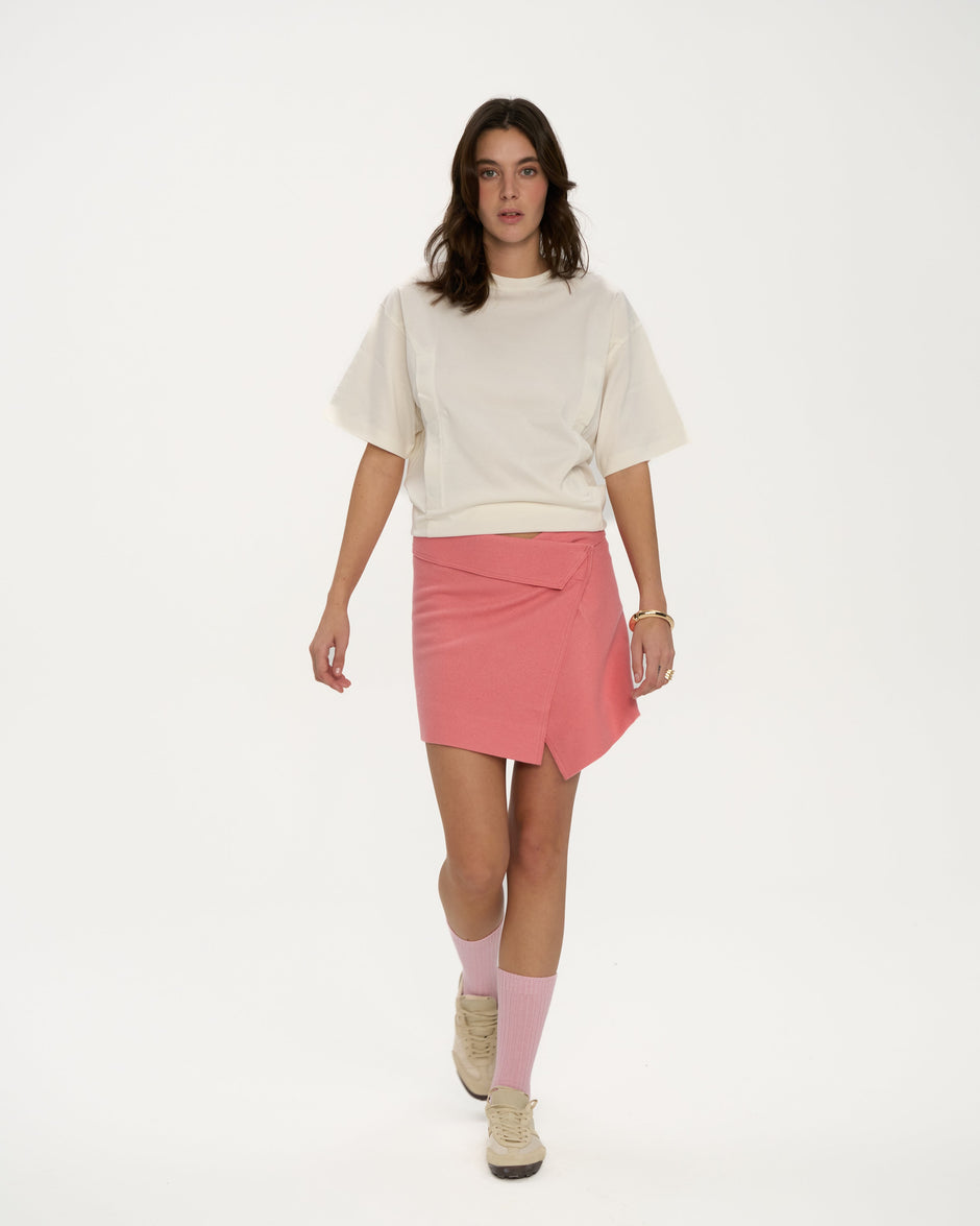 Woman wearing a white top and pink skirt on a white background