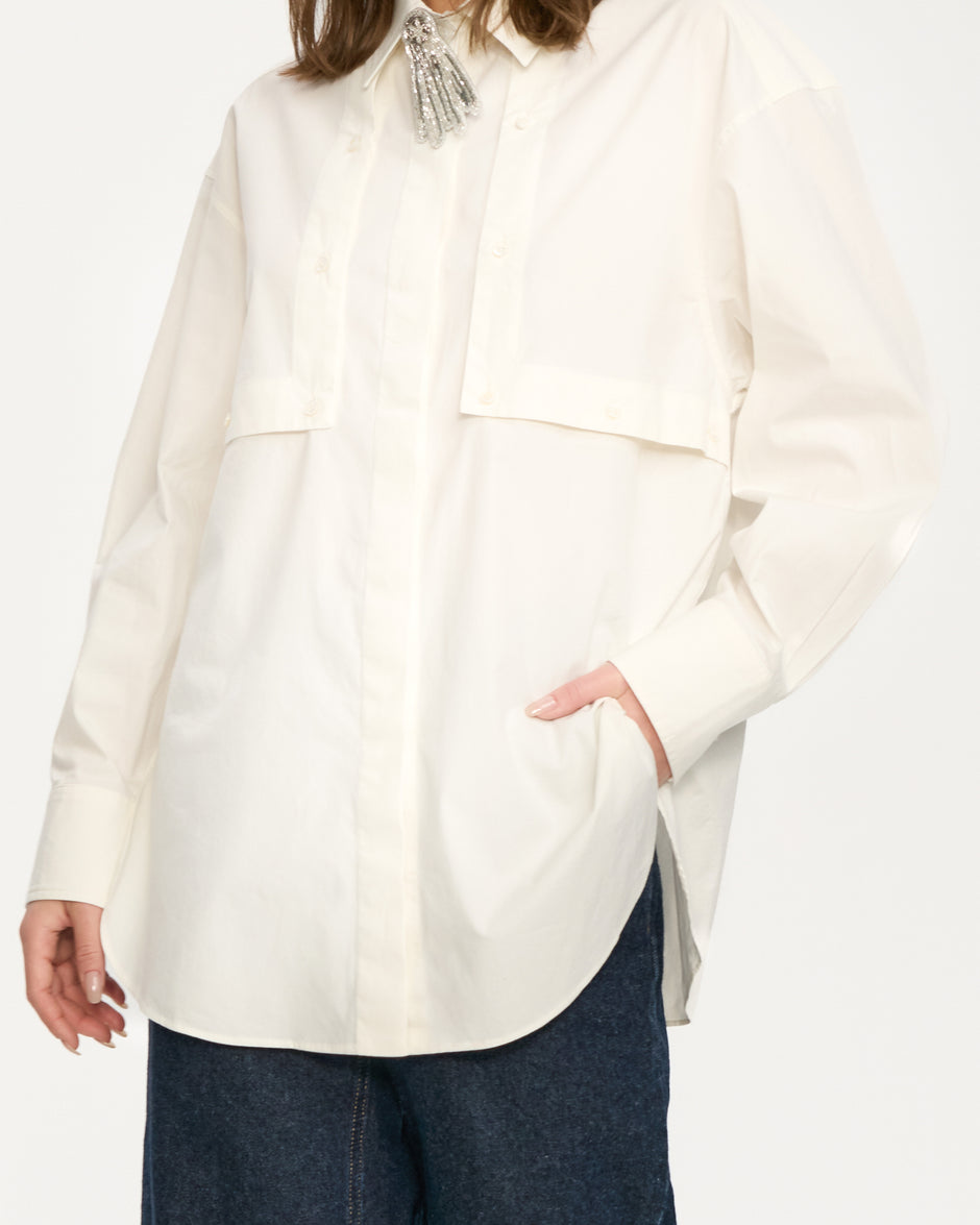 Person wearing a white layered shirt with a neutral background