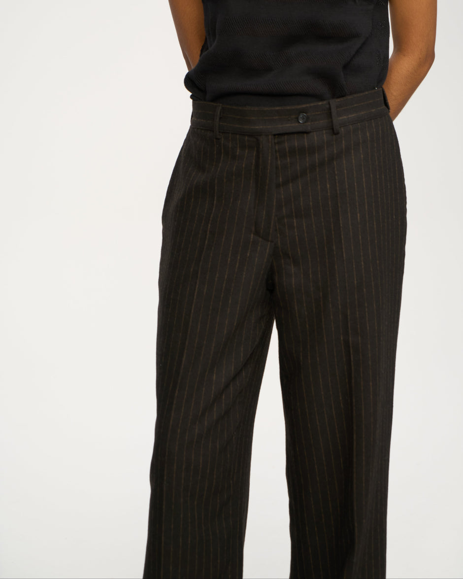 Person wearing black pinstripe pants and a black shirt on a white background