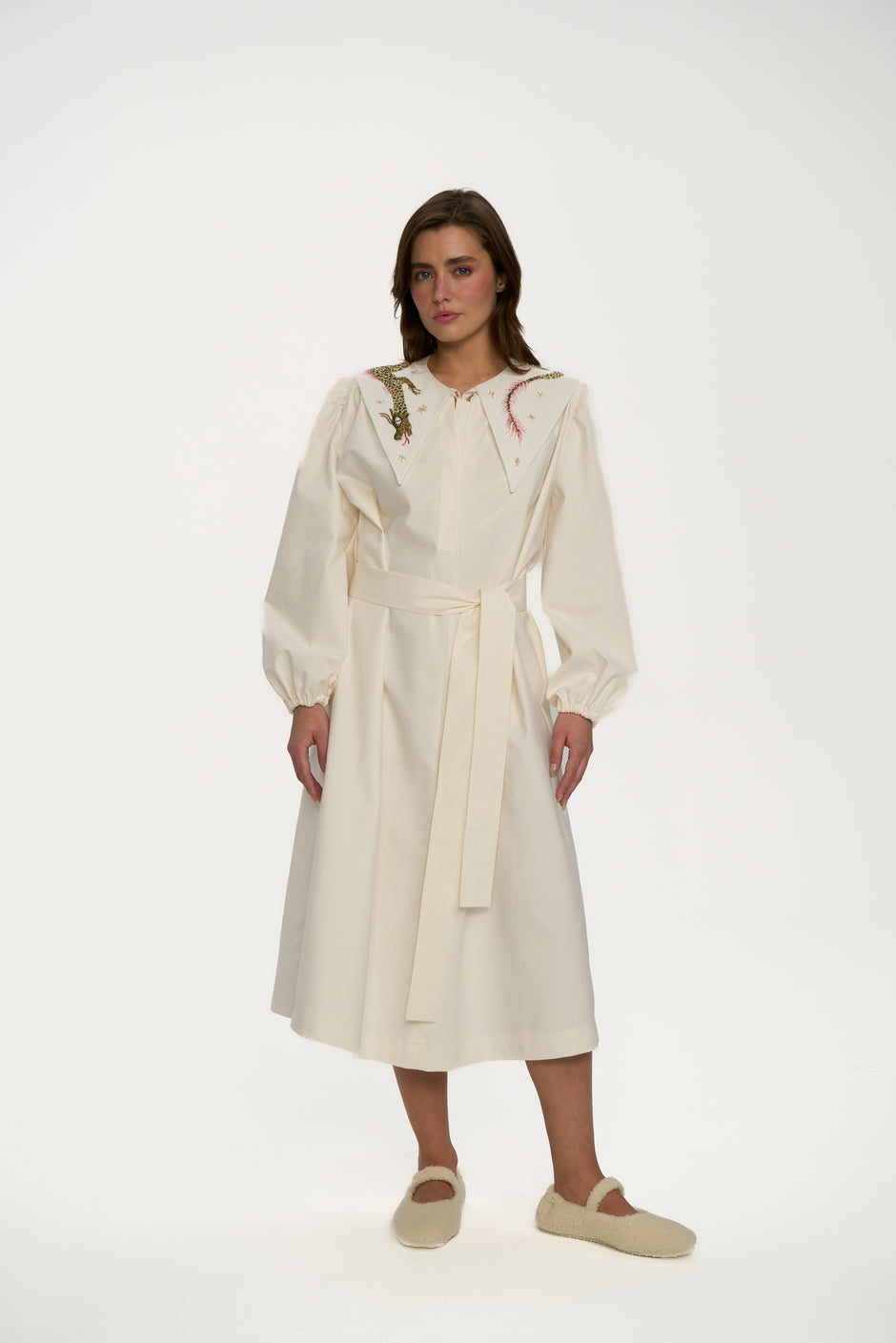 Woman wearing a long cream coat on a white background