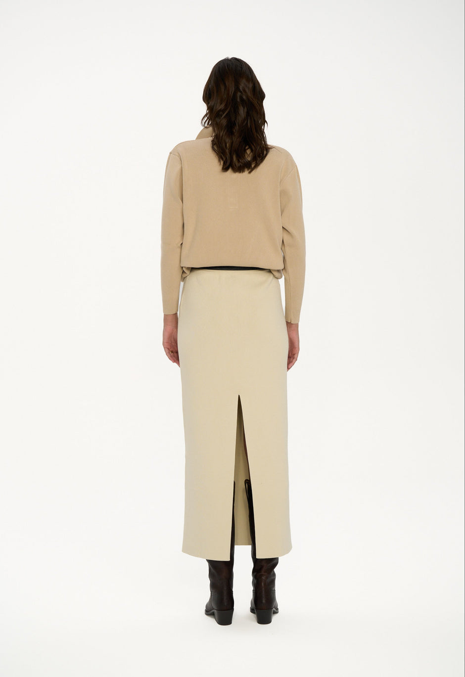 Woman wearing a beige sweater and long skirt on a white background